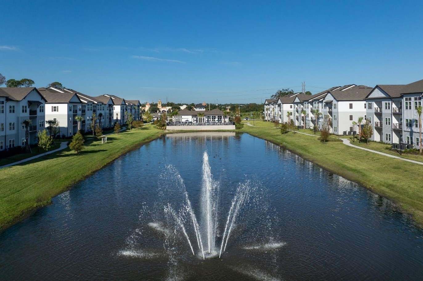 Residential buildings arranged around a landscaped pond with fountains