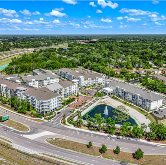 Aerial view of a residential site with access roads, green spaces and a retention pond